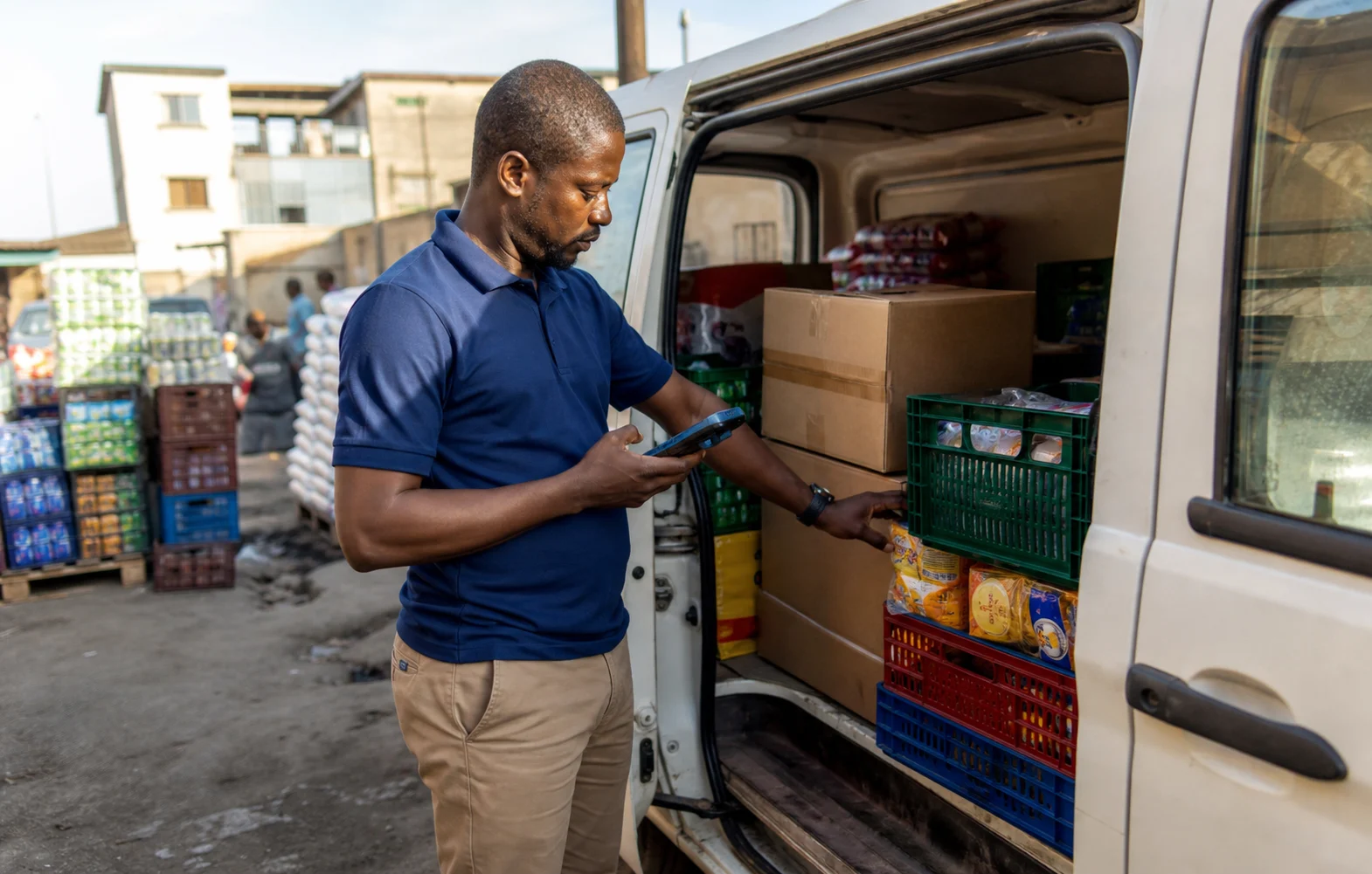 Field sales representative checking packaged goods beside a delivery van with an Android handheld